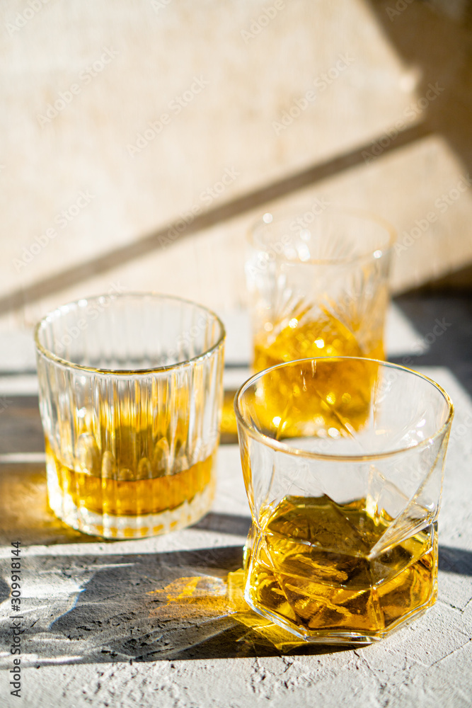 Whiskey in glasses on table in bright sunlight, yellow drink Whiskey in glasses on table in bright sunlight, yellow drink
