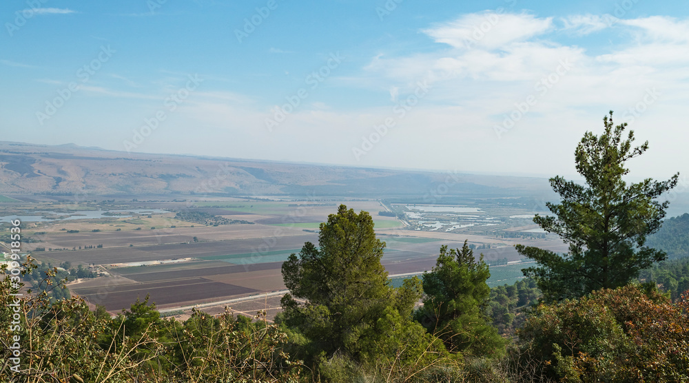 Hula Lake Park on the left and the hula nature reserve on the right from near the reut museum with trees in the foreground and the golan heights in the background