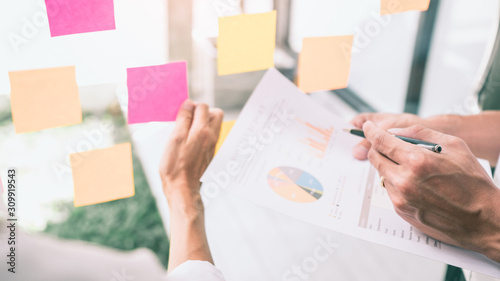 Business people meeting at office and use sticky notes on glass wall in office, diverse employees people group planning work together brainstorm strategy.