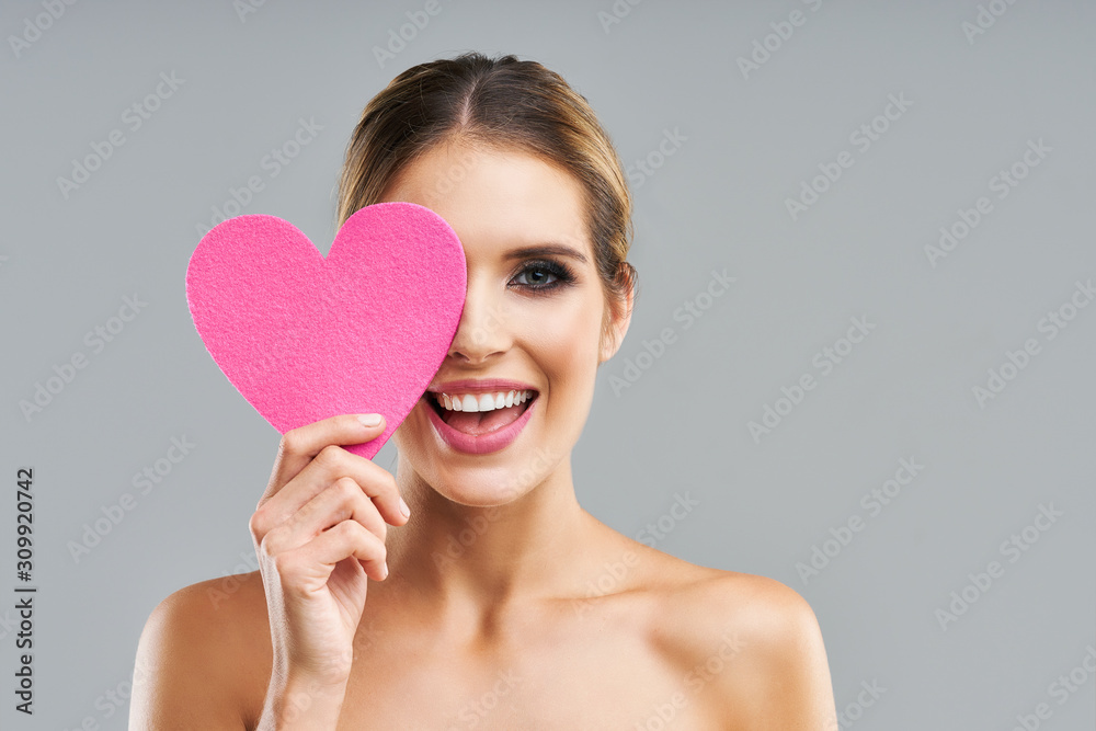 Beautiful adult woman posing over gray background with heart Beautiful adult woman posing over gray background with heart