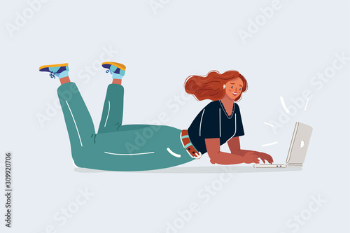 Woman working on a laptop lies on her stomach.