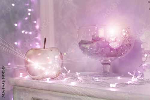 Christmas background with shiny colored toys. Background with blurred lights garlands, pink toys on one side of the picture. Pink details in the interior