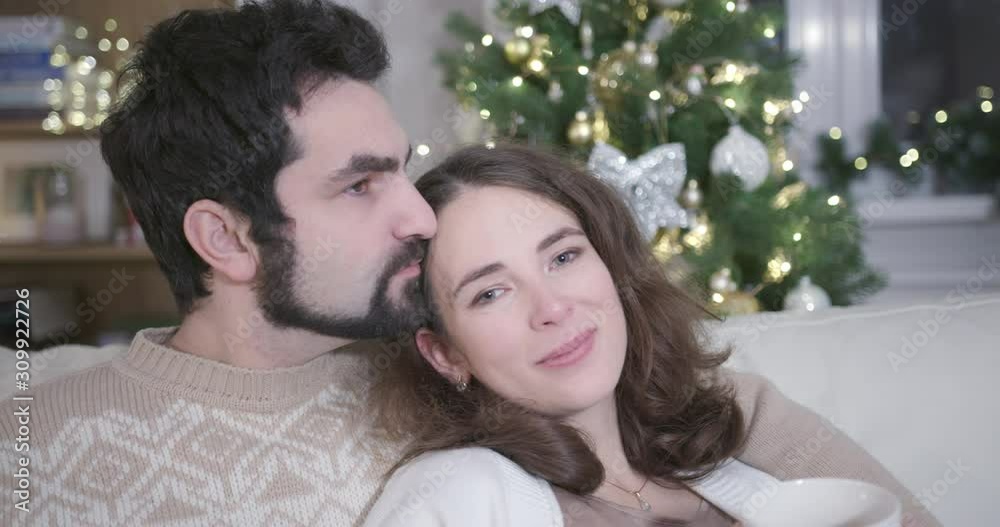 Sweet embrace of romantic couple. A Young family celebrates Christmas in White Interior. Concept of Love, Family, Holidays and Romance. Sweet embrace of romantic couple. A Young family celebrates Christmas in White Interior. Concept of Love, Family, Holidays and Romance.