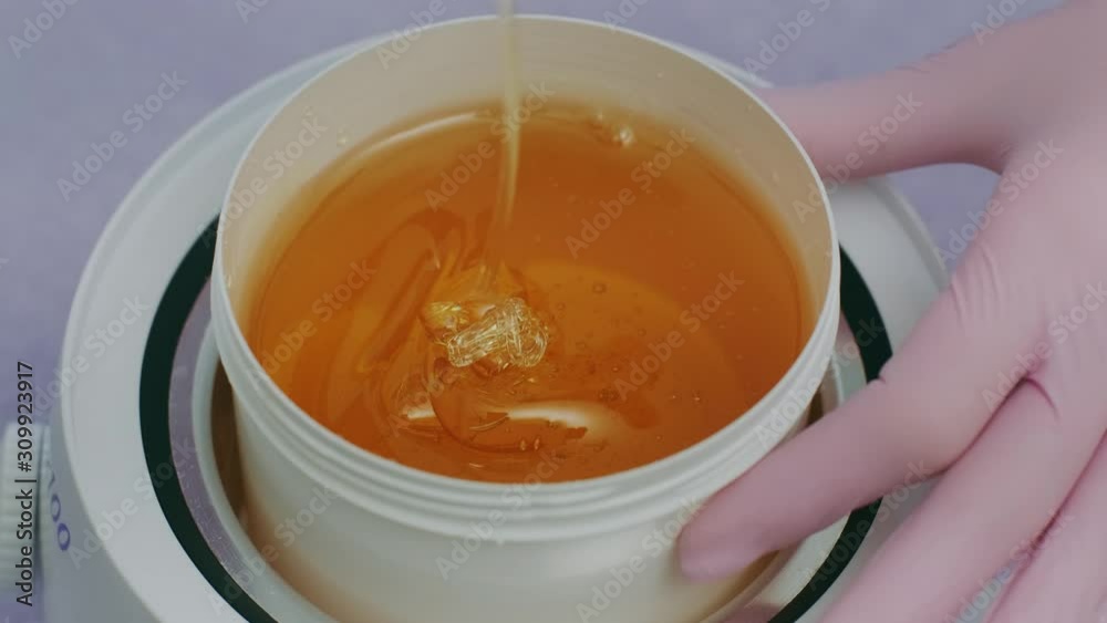 Liquid sugar for skin epilation. Close up shot. depilation and beauty concept - sugar paste or wax honey for hair removing with wooden waxing spatula sticks Liquid sugar for skin epilation. Close up shot. depilation and beauty concept - sugar paste or wax honey for hair removing with wooden waxing spatula sticks