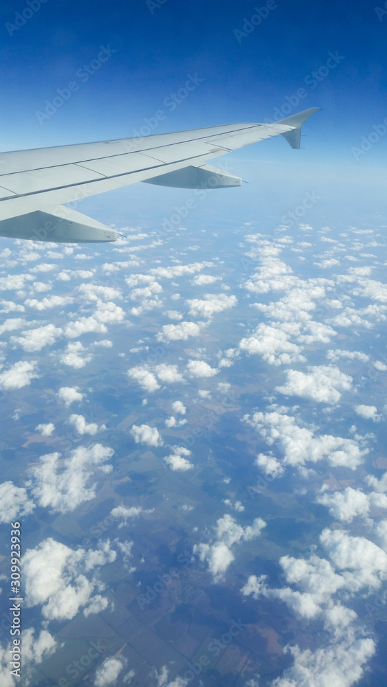 Fototapeta premium Wing of an airplane flying above the clouds