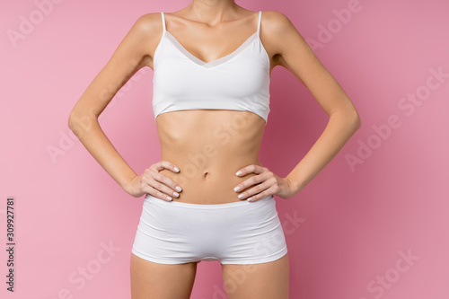 Cropped unrecognizable woman with perfect body and skin, sportive athletic body of young female isolated on pink background