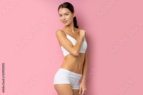 portrait of beautiful woman brunette posing in studio isolated over pink background. female have perfect body and skin