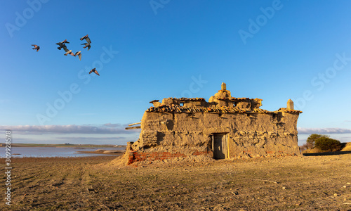 An old crumbled pigeon house made of clay in the Spanish region of Castilla y Leon in the north of the country. Pigeons can nest and breed in these houses. Pigeons in the air.