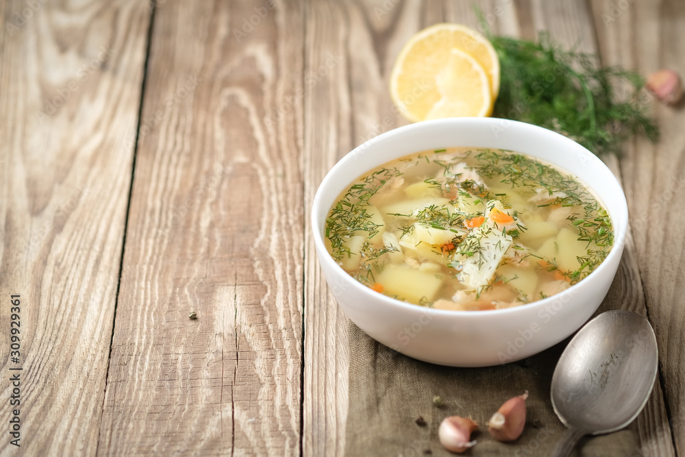 Fresh homemade fish soup with vegetables in bowl on rustic wooden background with copy space. Fresh homemade fish soup with vegetables in bowl on rustic wooden background with copy space.