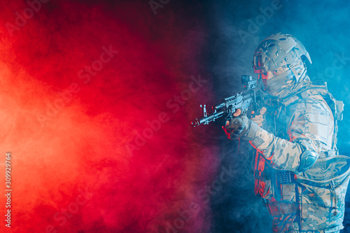 safety and protection concept. young man work as military man protecting country  wearing military forces clothes and holding gun in smoky UV space
