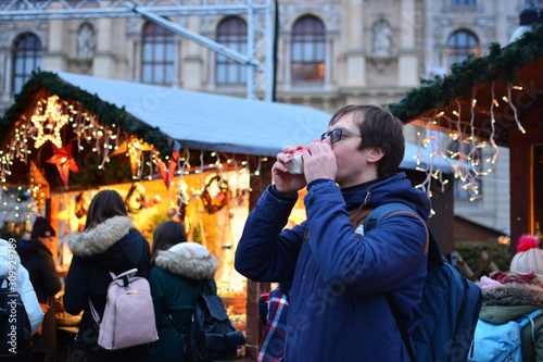 Canvas Print Tourist drinks mulled wine at the traditional Vienna Christmas market
