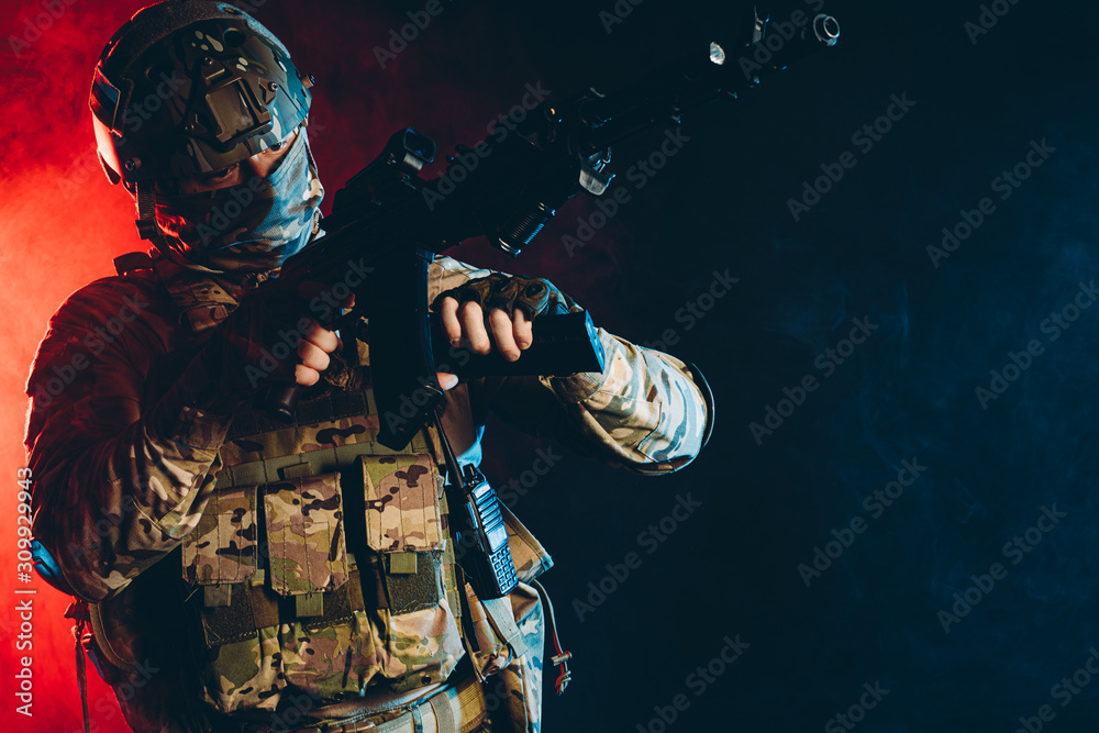 Fototapeta premium warrior military man wearing green uniform stand with gun rifle isolated over smoky background with ultra-violet rays, in search of enemy