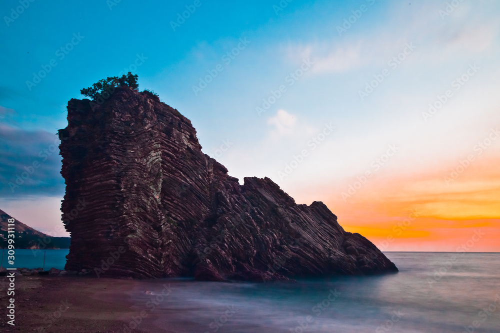 Rock with a pink and blue sky. Sunset sea romantic landscape with bright saturated colors, rock stones.