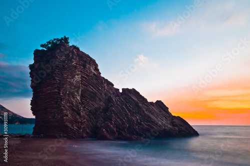 Rock with a pink and blue sky. Sunset sea romantic landscape with bright saturated colors, rock stones.