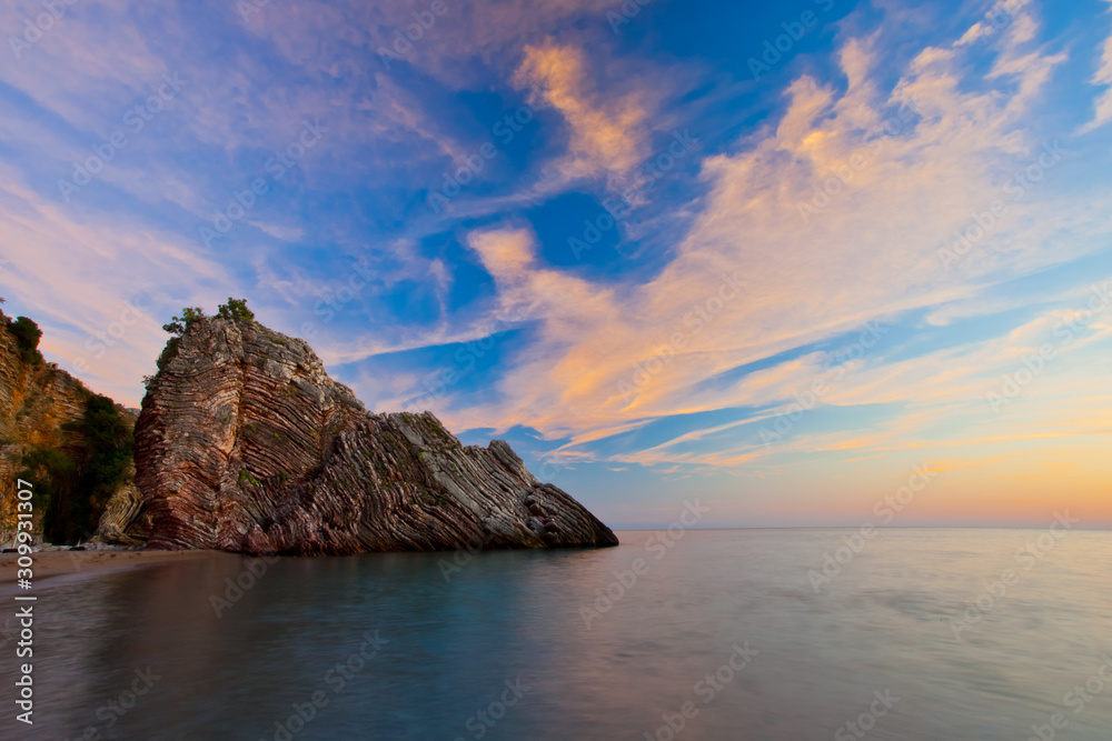 Cliff by the sea at sunset. Sunset sea romantic landscape with bright saturated colors, rock stones.