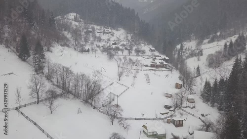 Calm and cosy fairy-tale village Kryvorivnia covered with snow in the Carpathians mountains, aerial view. Typical landscape in Hutsulshchyna National Park in Ukraine. Vacation and winter sports. photo