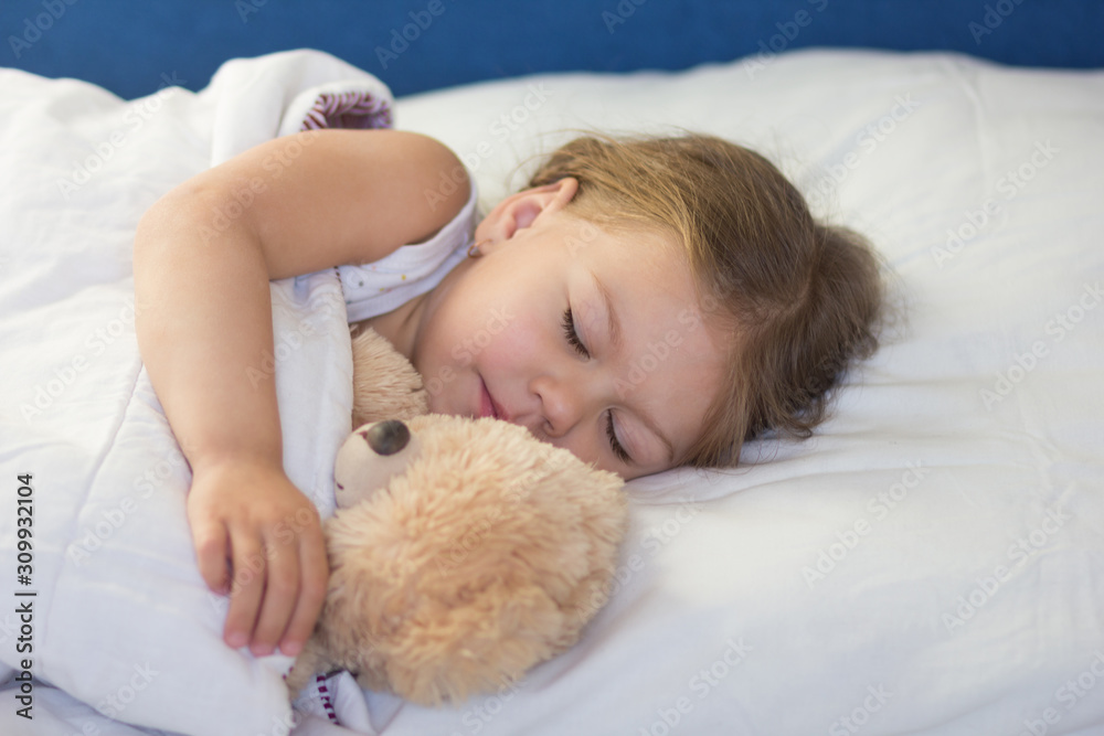 Caucasian child of three age sleeping in the bed with bear toy during day Caucasian child of three age sleeping in the bed with bear toy during day
