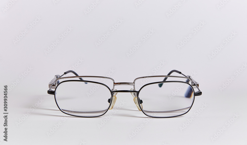 Fototapeta premium Two pairs of glasses are arranged one after another, like two people. Glasses close-up isolated on a white background