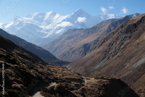 Mountain road with walking tourists on trail from Yak Kharka to Thorung Phedi, Himalaya, Nepal. During trekking around Annapurna, Annapurna Circuit