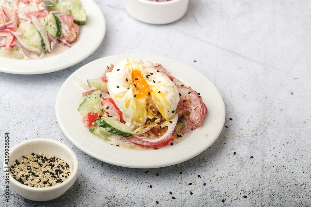 Poached egg on chopped and mixed vegetables with sour cream, scattered sesame seeds, white dishes Poached egg on chopped and mixed vegetables with sour cream, scattered sesame seeds, white dishes