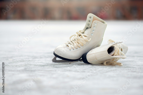 A pair of White Figure Skates lie on an open ice rink © borisenkoket