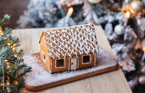 Homemade gingerbread house in front of Christmas tree