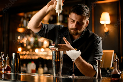 Bartender preparing sour mix with jigger and shaker