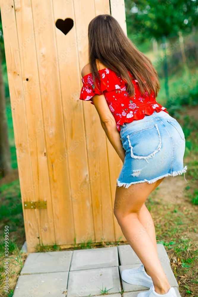 A girl in short jeans skirt waiting for wooden toiled Stock 写真 | Adobe Stock