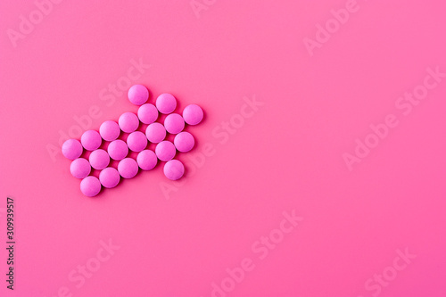 Close-up of pink pills lie on a pink surface