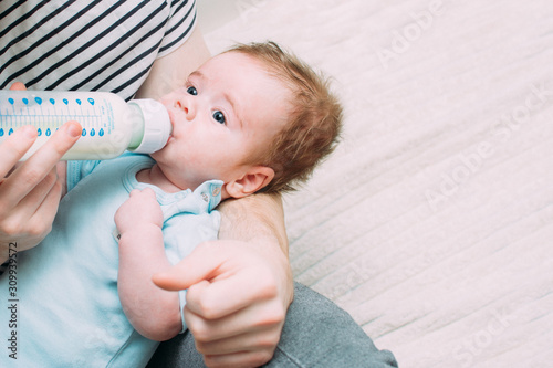 young father feeds his son with a bottle of milk. Man taking care of a child concept