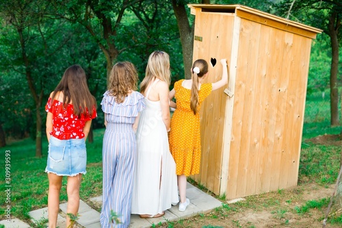 Girls and women waiting for outdoor wooden toilet