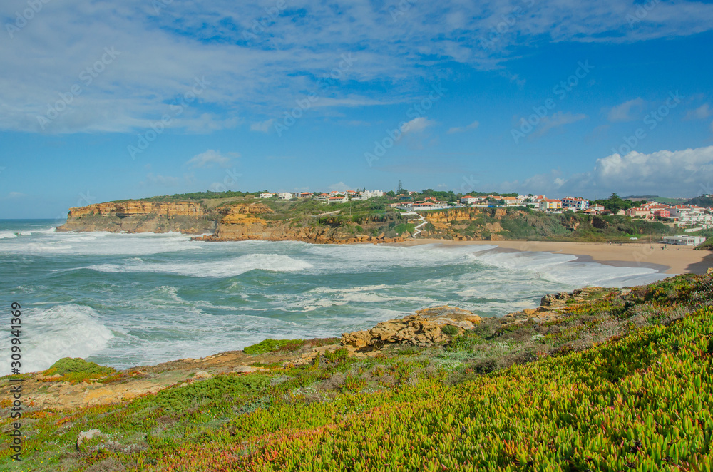 View of the Atlantic ocean, waves, picturesque village in Portugal. Panorama. Windy ocean in sunny day with bright colors.