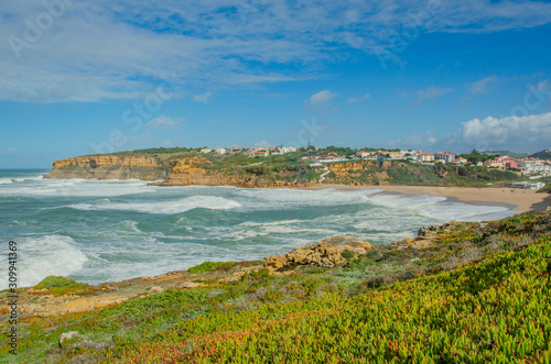 View of the Atlantic ocean, waves, picturesque village in Portugal. Panorama. Windy ocean in sunny day with bright colors.