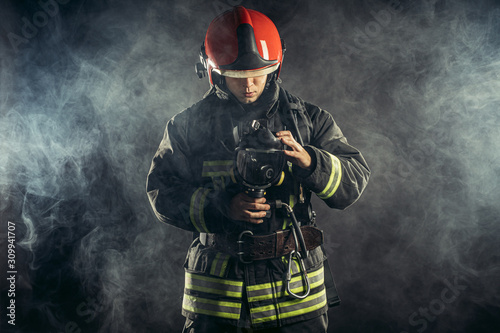 Fototapeta Naklejka Na Ścianę i Meble -  fireman or firefighter stand in smoke, professional worker of fire station in uniform, in helmet