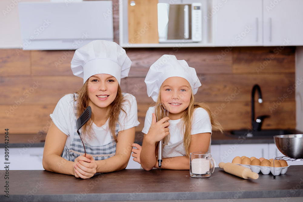 charming woman with child girl looking at camera, enjoy baking and cooking together in kitchen, beautiful family charming woman with child girl looking at camera, enjoy baking and cooking together in kitchen, beautiful family