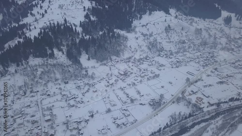 Calm and cosy fairy-tale village Kryvorivnia covered with snow in the Carpathians mountains, aerial view. Typical landscape in Hutsulshchyna National Park in Ukraine. Vacation and winter sports. photo