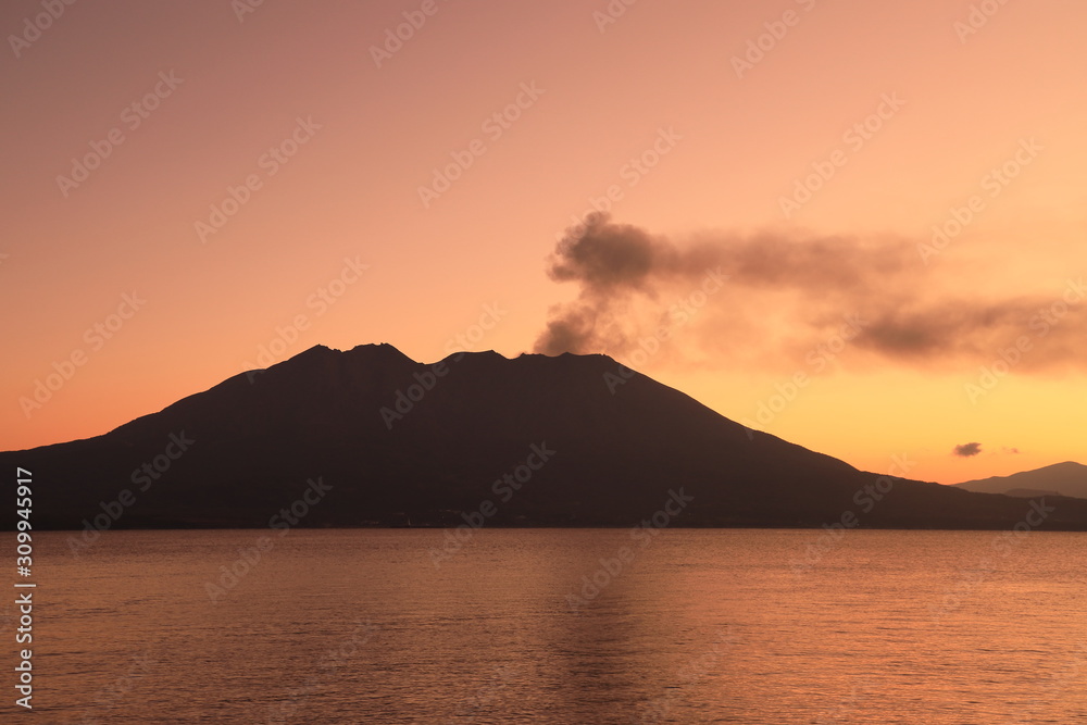 噴煙を上げる火山島の夜明け