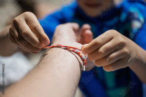Boy tying a string made bracelet to his fathers wrist