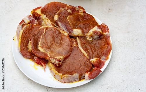 Raw pork steaks in marinade on a white plate photo