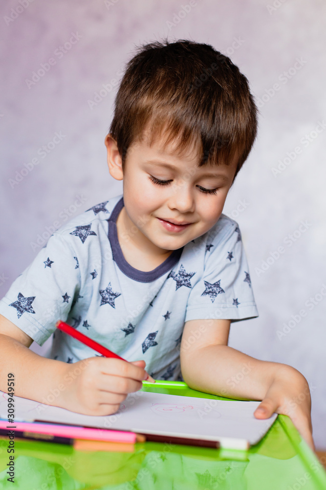 Little boy drawing with color pencils. Boy, drawing a picture for fathers day. Small boy draws at the table. Little boy drawing with color pencils. Boy, drawing a picture for fathers day. Small boy draws at the table.