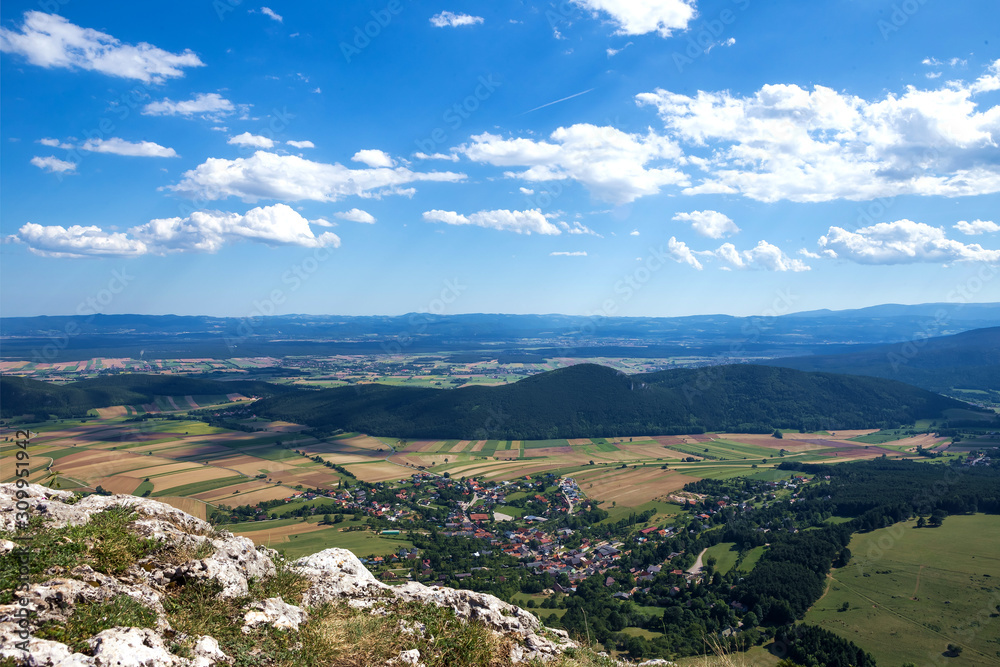 Panoramic views of the sky above Hohe Wand. Above are beautiful clouds in the blue sky, and below are forests and fields.