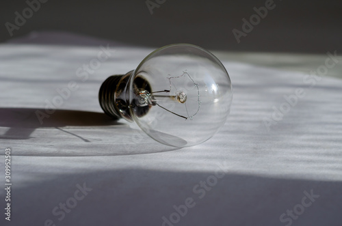 Tungsten light bulb. Close-up of a previous generation electric lamp. Obsolete electrical goods. Selective focus. Eye level shooting. photo