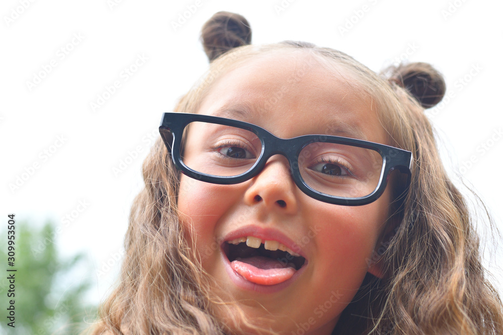 Portrait of beautiful young first-grader girl in eyeglasses. Focus on girls eyes Portrait of beautiful young first-grader girl in eyeglasses. Focus on girls eyes