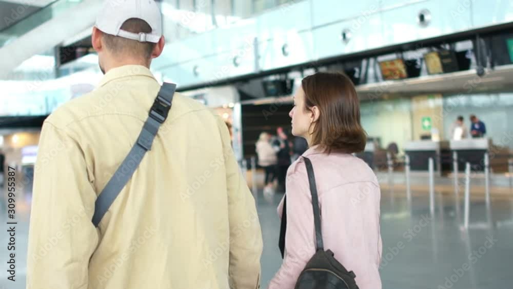Husband escorts his wife on a plane, a close-up of a man and a woman are walking with a suitcase at the airport station. Couple late for flight, flight departure Husband escorts his wife on a plane, a close-up of a man and a woman are walking with a suitcase at the airport station. Couple late for flight, flight departure
