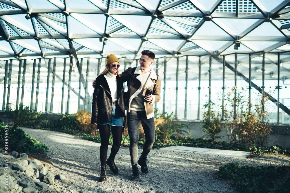 Happy couple walking in embrace in bright botanic garden Happy couple walking in embrace in bright botanic garden