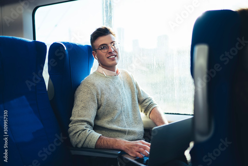 Smiling young traveler browsing laptop while sitting in train © GalakticDreamer