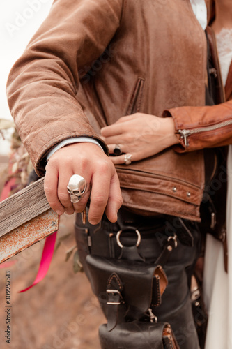 Romance of bikers. Man and woman hold hands. Hands with rings. Leather jackets. Autumn wedding in nature