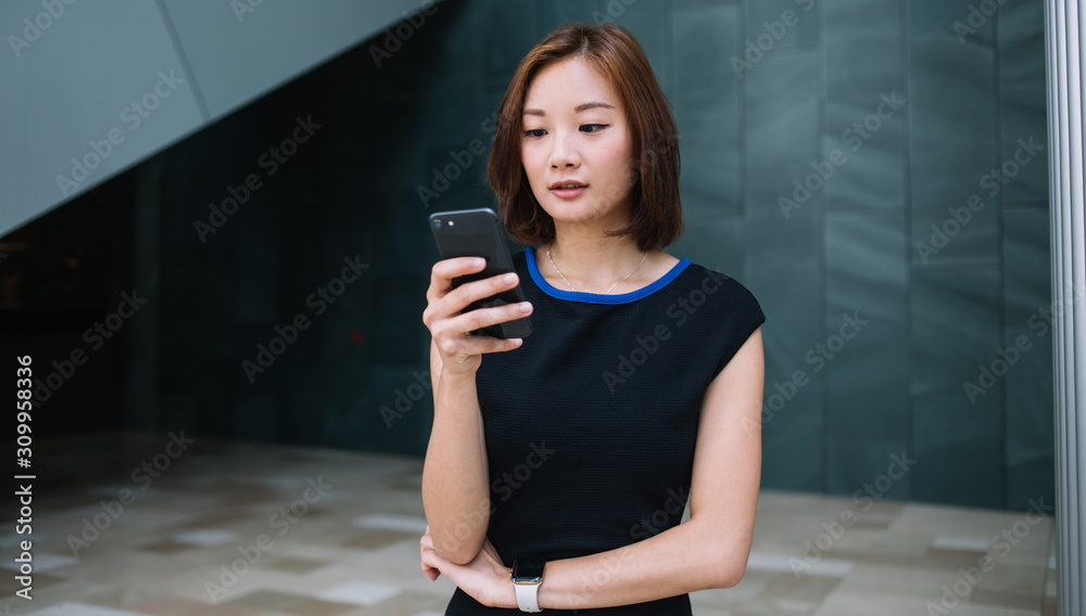 Young ethnic woman carefully reading message on smartphone