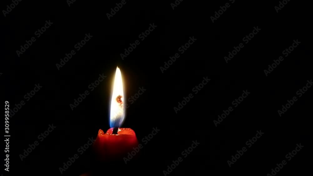 Red burning candle on black background Red burning candle on black background
