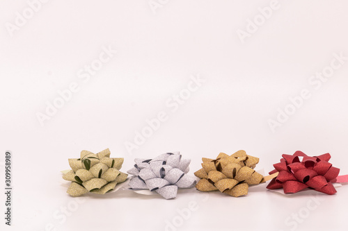 Noël anniversaire préparation des cadeaux rangée de nœuds bolduc argent or et rouge sur fond blanc avec espace texte